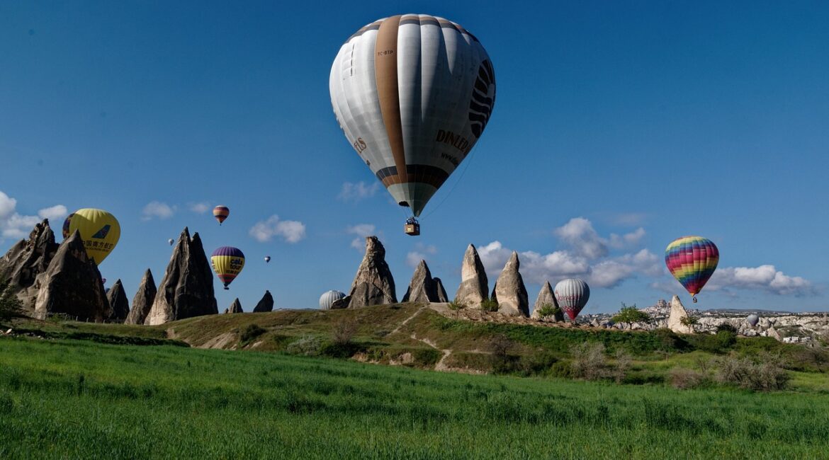 Hot air balloons floating over fairy chimneys in Cappadocia's valley during a clear morning