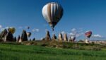 Hot air balloons floating over fairy chimneys in Cappadocia's valley during a clear morning