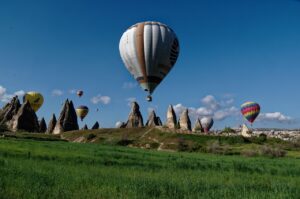 Hot air balloons floating over fairy chimneys in Cappadocia's valley during a clear morning