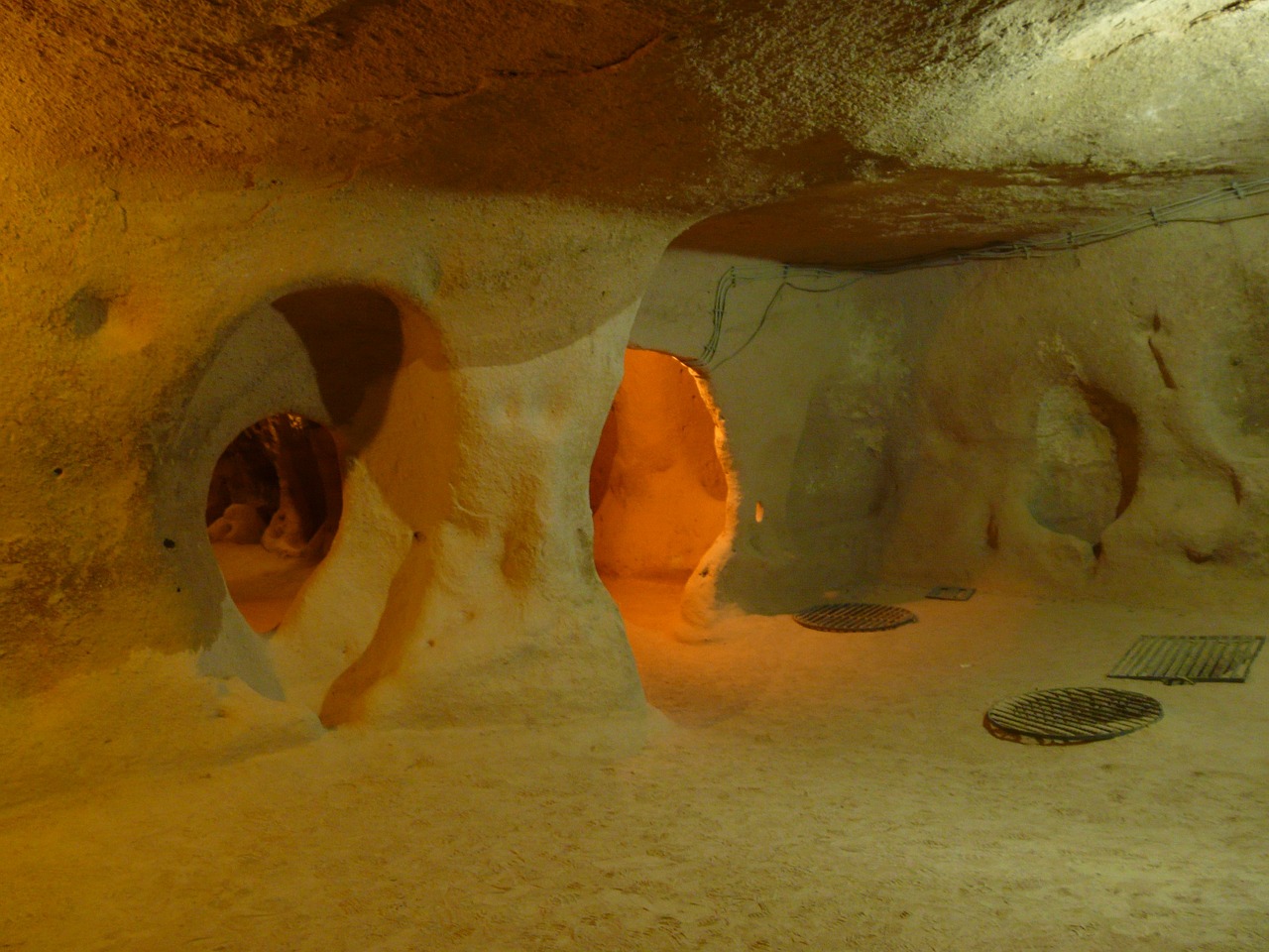 Ancient underground tunnels illuminated by amber lights showing carved passages in Derinkuyu Underground City
